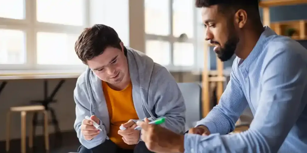 Two men discussing support options under NDIS while reviewing documents together