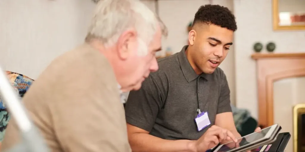 NDIS support worker assisting an elderly man with a digital tablet at home