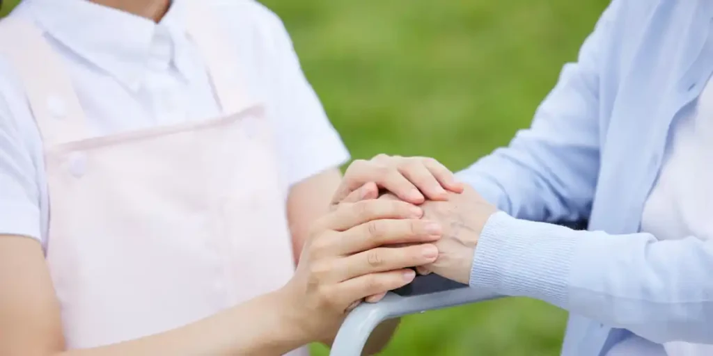 A caregiver and elderly person placing their hands together in a gesture of trust and support, representing professional carer support services on the Gold Coast.
